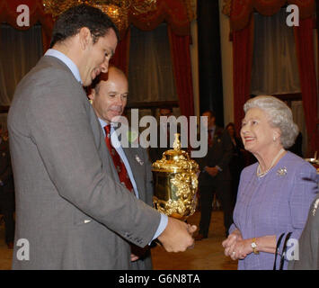 La Regina Elisabetta II incontra il capitano di rugby inglese Martin Johnson e l'allenatore Clive Woodward a Buckingham Palace, Londra. In precedenza la squadra aveva sfilato il trofeo William Ellis attraverso il West End in una processione di autobus scoperto. 17/01/04: Il capitano inglese dovrebbe annunciare il suo ritiro dalla partita internazionale dopo la partita della Leicester's Heineken Cup con Ulster, sabato 17 gennaio 2004. Foto Stock