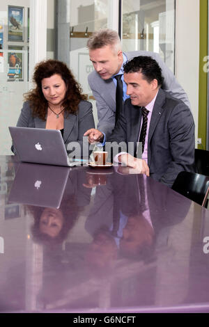Fiducioso e business di successo di persone il brainstorming di idee in un grande ufficio moderno di fronte lo schermo del computer portatile Foto Stock