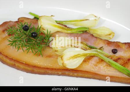 Pancetta fritta con la cipolla e il ginepro nel piatto Foto Stock