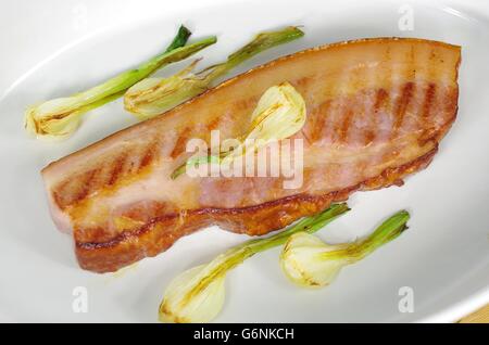 Pancetta fritta con la cipolla e il ginepro nel piatto Foto Stock