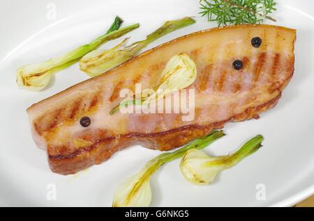 Pancetta fritta con la cipolla e il ginepro nel piatto Foto Stock