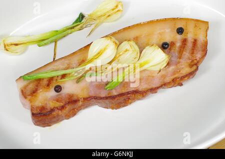 Pancetta fritta con la cipolla e il ginepro nel piatto Foto Stock