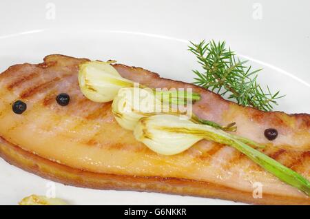 Pancetta fritta con la cipolla e il ginepro nel piatto Foto Stock