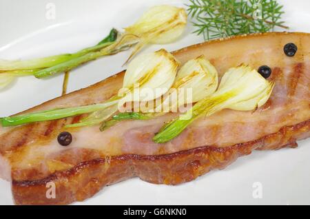 Pancetta fritta con la cipolla e il ginepro nel piatto Foto Stock