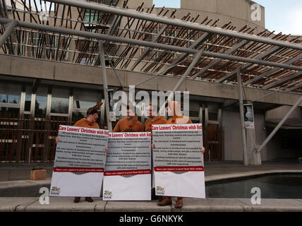 I giovani che abbandonano l'assistenza e i membri del personale delle organizzazioni giovanili presentano una gigantesca cartolina di Natale con una lista dei desideri agli MSP al Parlamento scozzese di Edimburgo. Foto Stock