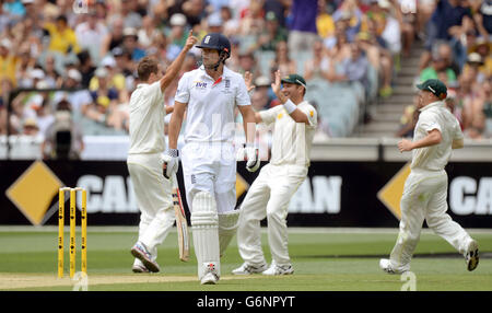 L'australiano Peter Siddle (a sinistra) festeggia come l'inglese Alastair Cook (al centro) lascia il campo dopo essere stato catturato dall'australiano Michael Clarke (non illustrato) per 27 corse durante il primo giorno del quarto test al MCG di Melbourne, Australia. Foto Stock