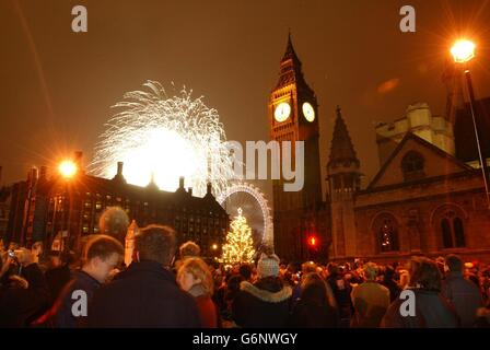 I rivelatori in Parliament Square guardano come i fuochi d'artificio esplodono sopra il London Eye per segnare l'arrivo nel Regno Unito di 2004. Foto Stock