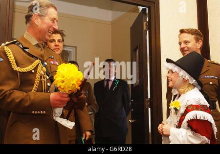 Il Principe di Galles è presentato con un mazzo di narcisi di Charlotte Regan, 12 anni, al RAF St Athan nel Galles del Sud. Charles stava accogliendo i soldati della compagnia del Principe di Galles, la prima Battaglione Guardie gallesi quando arrivarono dall'Irlanda del Nord dopo un tour di 11 mesi. Foto Stock