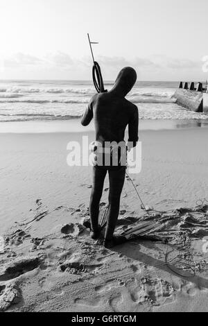 Non identificato subacqueo con la pesca subacquea pistola sulla spiaggia entra nell oceano onde Foto Stock