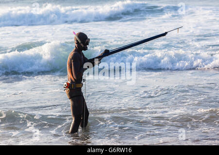 Non identificato subacqueo con la pesca subacquea pistola sulla spiaggia entra nell oceano onde Foto Stock