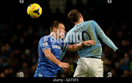 John Terry di Chelsea batte per la palla con Edin Dzeko di Manchester City, durante la partita della Barclays Premier League all'Etihad Stadium di Manchester. Foto Stock