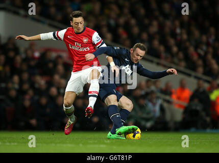 L'Arsenal's Mesut Ozil (a sinistra) combatte per il possesso della palla con Wayne Rooney di Manchester United Foto Stock