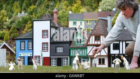 Il giardiniere Robert Gagie riposiziona i giocatori per una partita di cricket sul green al Babbacombe Model Village vicino a Torquay in Devon. Il villaggio è iniziato come una rappresentazione della quintessenza della campagna inglese alla sua più bella 40 anni fa. Da allora il progetto è cresciuto e ora presenta una vasta gamma di edifici, mulini ad acqua in funzione, città georgiane, case tudor e classici villaggi e fattorie con tetto in paglia Devon insieme a ferrovie in funzione, ruscelli, cascate e un lago ornamentale rifornito di esemplari di carpa Koi. Foto Stock