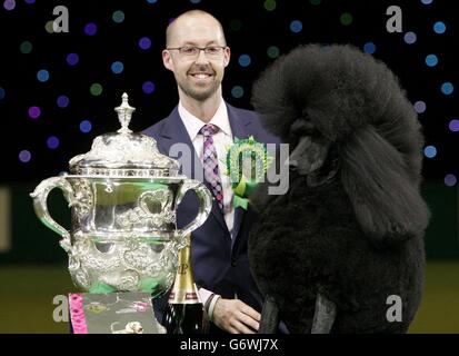 Il poodle standard di due anni Ricky con il suo gestore Jason Lynn, dopo aver vinto il premio più prestigioso al mondo per la mostra di cani dopo essere stato giudicato il Best-in-Show di quest'anno al Crufts al NEC di Birmingham. Foto Stock