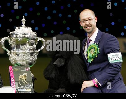 Il poodle standard di due anni Ricky con il suo gestore Jason Lynn, dopo aver vinto il premio più prestigioso al mondo per la mostra di cani dopo essere stato giudicato il Best-in-Show di quest'anno al Crufts al NEC di Birmingham. Foto Stock