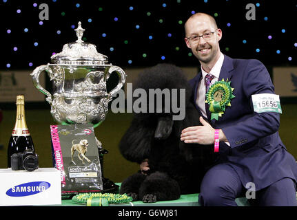 Il poodle standard di due anni Ricky con il suo gestore Jason Lynn, dopo aver vinto il premio più prestigioso al mondo per la mostra di cani dopo essere stato giudicato il Best-in-Show di quest'anno al Crufts al NEC di Birmingham. Foto Stock