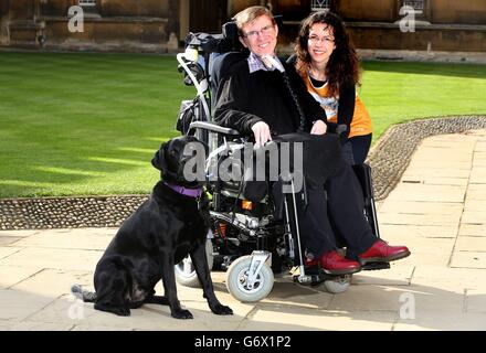 Studente di dottorato Jonathan Gilmour che ha la distrofia muscolare di Duchenne con il suo cane di assistenza Uri e l'allevatore di fondi Albertyna Paciorek nel cortile del college di St John all'Università di Cambridge. Foto Stock