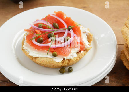 Casa sana realizzati senza glutine biscotto con salmone affumicato lox, crema di formaggio, capperi e cipolla rossa le fette su piastra bianca in horizo Foto Stock