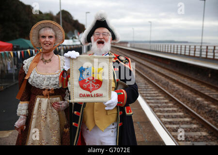 Il comune Crier Steve Cunliffe e sua moglie Caroline Cunliffe si trovano sulla piattaforma ferroviaria della stazione ferroviaria di Dawlish durante una visita del primo ministro David Cameron dopo la riapertura della linea ferroviaria devastata dalla tempesta. Foto Stock