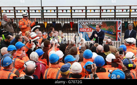 Il primo ministro David Cameron si rivolge ai lavoratori ferroviari durante una visita alla stazione ferroviaria di Dawlish a Dawlish, Devon, dopo la riapertura della linea ferroviaria distrutta dalla tempesta. Foto Stock