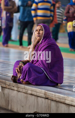 Unidentified le donne indiane in viola sari seduti vicino al lago, a tempio d'Oro Foto Stock