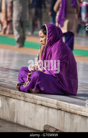 Unidentified le donne indiane in viola sari seduti vicino al lago, a tempio d'Oro Foto Stock