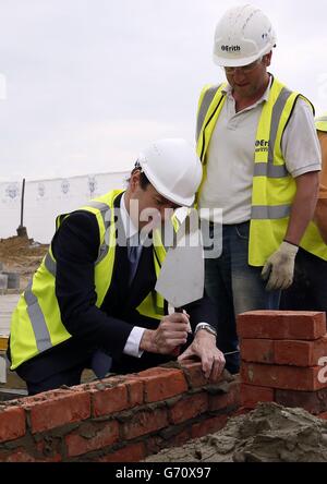 Il Cancelliere dello scacchiere George Osborne (a sinistra) depone mattoni mentre visita il cantiere per la città giardino di Ebbsfeet, Kent. Foto Stock