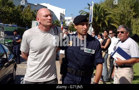 Un ufficiale di polizia conduce Garry Mann, 46 anni, di Faversham a Kent in un tribunale ad Albufeira dove 12 fan inglesi stavano comparendo dopo che i combattimenti sono scoppiati lunedì sera vicino al bar la Bamba. *17/06/04: Garry Mann, di Faversham in Kent, divenne il primo fan inglese ad essere incarcerato a Euro 2004 quando ricevette una sentenza di due anni per aver partecipato ad una rivolta nell'Algarve. Egli servirà la sentenza in Inghilterra. Foto Stock