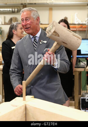 Il Principe del Galles martella in un piolo con un gigantesco martello mentre visita il reparto di lavorazione del legno al centro per la scienza applicata e la tecnologia all'Holland College di Charlottetown, Canada, il terzo giorno del suo viaggio reale in Canada. Foto Stock