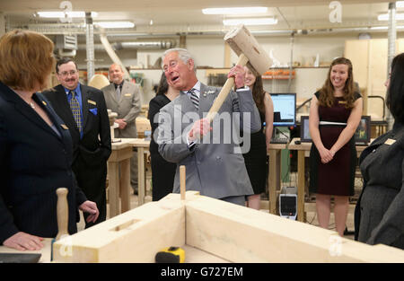 Il Principe del Galles martella in un piolo con un gigantesco martello mentre visita il reparto di lavorazione del legno al centro per la scienza applicata e la tecnologia all'Holland College di Charlottetown, Canada, il terzo giorno del suo viaggio reale in Canada. Foto Stock