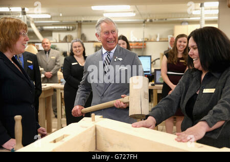 Il Principe del Galles martella in un piolo con un gigantesco martello mentre visita il reparto di lavorazione del legno al centro per la scienza applicata e la tecnologia all'Holland College di Charlottetown, Canada, il terzo giorno del suo viaggio reale in Canada. Foto Stock