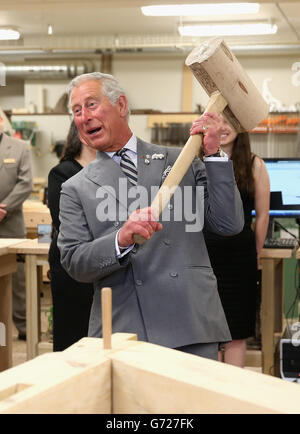 Il Principe del Galles martella in un piolo con un gigantesco martello mentre visita il reparto di lavorazione del legno al centro per la scienza applicata e la tecnologia all'Holland College di Charlottetown, Canada, il terzo giorno del suo viaggio reale in Canada. Foto Stock