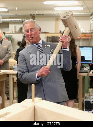 Il Principe del Galles martella in un piolo con un gigantesco martello mentre visita il reparto di lavorazione del legno al centro per la scienza applicata e la tecnologia all'Holland College di Charlottetown, Canada, il terzo giorno del suo viaggio reale in Canada. Foto Stock