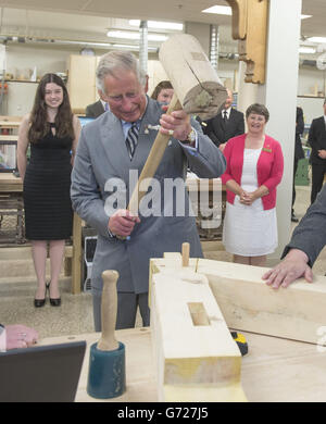 Il Principe del Galles martella in un piolo con un gigantesco martello mentre visita il reparto di lavorazione del legno al centro per la scienza applicata e la tecnologia all'Holland College di Charlottetown, Canada, il terzo giorno del suo viaggio reale in Canada. Foto Stock