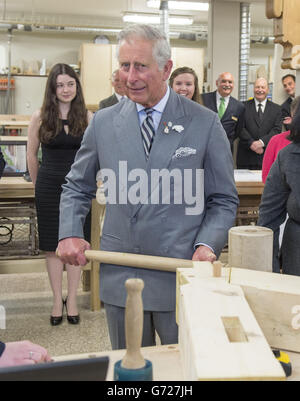 Il Principe del Galles martella in un piolo con un gigantesco martello mentre visita il reparto di lavorazione del legno al centro per la scienza applicata e la tecnologia all'Holland College di Charlottetown, Canada, il terzo giorno del suo viaggio reale in Canada. Foto Stock