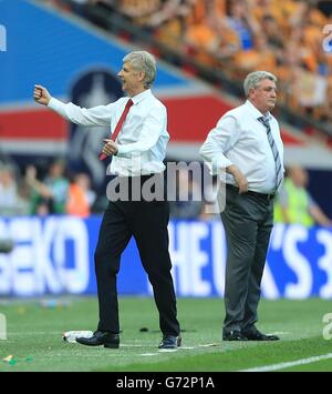 Il manager Arsenal Arsene Wenger (a sinistra) festeggia al fischio finale Come il manager di Hull City Steve Bruce guarda sopra Foto Stock