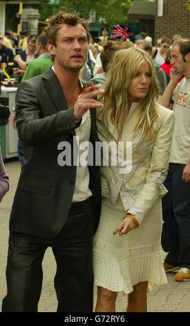 L'attore Jude Law e la sua fidanzata Sienna Miller arrivano ai Campionati di tennis di prato per assistere all'incontro di Tim Henman con Mario Ancic dalla Croazia nel quarto finale dei Men's Singles a Wimbledon, Londra. SOLO PER USO EDITORIALE, SENZA USO DI TELEFONO CELLULARE. Foto Stock