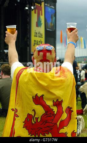 Un festaiolo dipinto con il logo T-in the Park che guarda al palco principale durante l'evento del festival musicale di due giorni a Balado, vicino a Stirling. Foto Stock