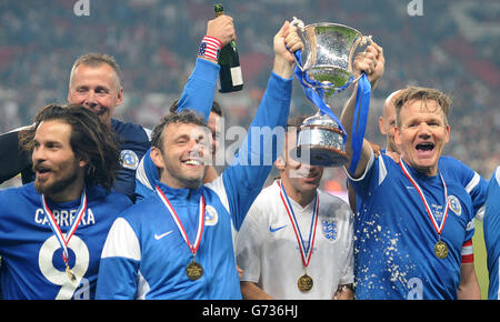 Michael Sheen e Gordon Ramsay del resto del mondo alzano il trofeo dopo aver vinto la partita di beneficenza Soccer Aid contro l'Inghilterra, a Old Trafford, Manchester. Foto Stock