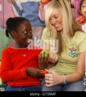 Ex- Atomic Kitten Liz McClarnon e 7-year-old Denise Tetteh durante una fotocellula alla Ashmead School nel sud di Londra, al lancio della campagna 'Fruit is Cool' sponsorizzata da Cape Apples per promuovere un'alimentazione sana tra i 7-16 anni. La ricerca effettuata da Cape ha rivelato che i bambini stanno spendendo quasi la metà del loro reddito mensile sui dolci, sui croccanti e sul cioccolato. Foto Stock