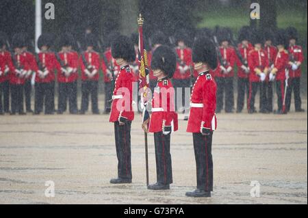 Durante la Revisione del colonnello, la prova finale di Trooping the Color, la parata annuale di compleanno della Regina, nel centro di Londra, si tengono sotto la pioggia le guardie granadier. Foto Stock