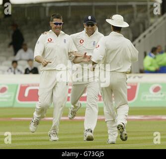 L'avvincente britannico Ashley Giles (a sinistra) festeggia con Marcus Trescosick (al centro) e il capitano Michael Vaughan (a destra) dopo aver preso il wicket indiano occidentale di Dwaye Bravo, durante l'ultimo giorno della prima prova della potenza npower a Lord's. Foto Stock