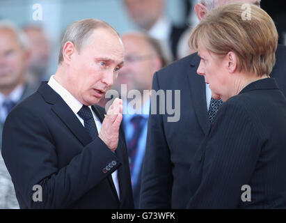 Il presidente russo Vladimir Putin ha parlato con la cancelliera tedesca Angela Merkel durante una cerimonia internazionale con i capi di Stato a Sword Beach in Normandia per celebrare il 70° anniversario degli sbarchi del D-Day. Foto Stock