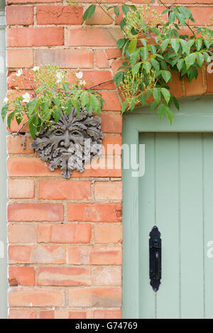 Scolpiti uomo verde placca / vaso su un muro di casa. Cotswolds, Inghilterra Foto Stock