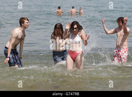 I festaioli Zoe Abbott (centro) e Rachel Gates (centro a sinistra) vengono spruzzati dall'acqua dai loro amici in mare sulla spiaggia di Ryde, prima di dirigersi al Festival dell'Isola di Wight. Foto Stock