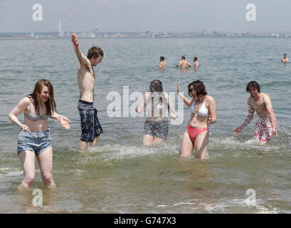 Il goer del festival Zoe Abbott (centro) viene spruzzato dall'acqua dai loro amici nel mare alla spiaggia di Ryde, prima di dirigersi al festival dell'isola di Wight. Foto Stock