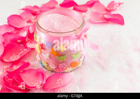 Rosa rosa su petali di rosa e di sale da bagno in una giara Foto Stock