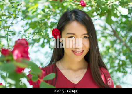 Donna in abito rosso con una rosa rossa tra i capelli Foto Stock