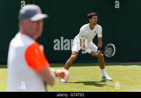 Le pratiche di Novak Djokovic sorvegliate dal suo allenatore Boris Becker sui campi di pratica di Aorangi all'All England Lawn Tennis and Croquet Club, Wimbledon. Foto Stock