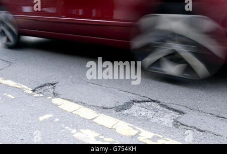 Stock di potole. Un'auto guida su una buche su una strada a Kimberley, Nottingham Foto Stock